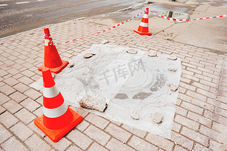 塑料红色锥体警告行人有关人行道和污水排放口的维修工作。