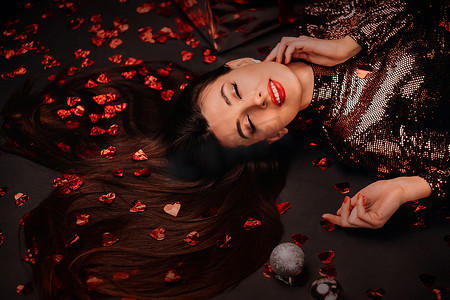 一个女孩穿着闪亮的衣服躺在地板上的头像，上面是心形的五彩纸屑