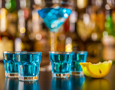 流行的蓝色饮料在酒吧的背景上用瓶子射击 kamikaze，这是一种清爽的饮料