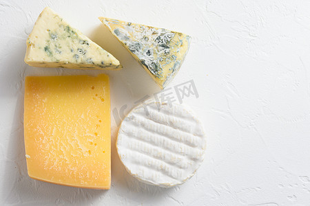 camembert摄影照片_奶酪拼盘：白色背景上的黄色 Maasdam、白色 Camembert 和蓝色奶酪 Dor Blue。