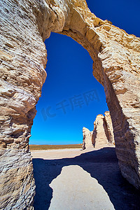 拱形穿过沙漠中的白色石头，蓝天