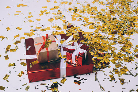 圣诞礼物、金色五彩纸屑、用白色和红色丝带包裹的节日圣诞礼物、假日设计