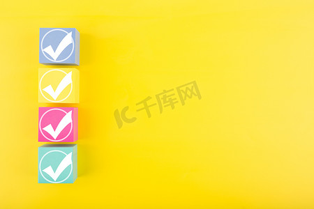 彩色玩具立方体上连续四个白色复选标记，背景为亮黄色，有复制空间