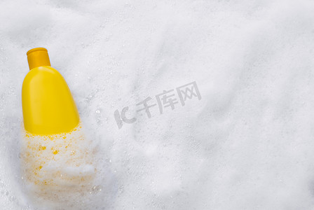 面霜背景摄影照片_黄色塑料管的模型，带有保湿霜、沐浴露、洗发水或洗面奶，以及白色背景上带气泡的温和肥皂泡，顶视图。