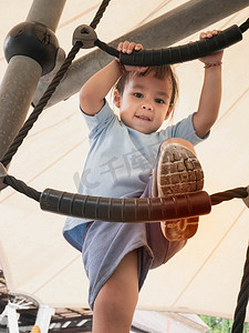 夏天，亚洲小女孩在操场上爬绳子很有趣。