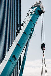 玻璃现代建筑附近带吊钩的蓝色起重机升降机构、起重机和液压升降机高达 120 米