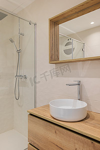 带淋浴、圆形白色水槽、木制底座和镜框的现代浴室。