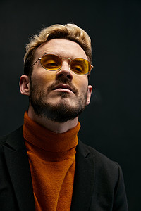 一个戴眼镜的时髦男人的肖像和秋季新品的橙色毛衣夹克趋势