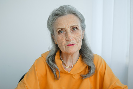 老女性摄影照片_美丽的老祖母的画像，头发灰白，脸上满是皱纹，看着镜头，母亲节，退休快乐