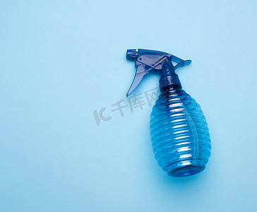 蓝色塑料瓶摄影照片_蓝色背景中带喷雾的透明塑料瓶