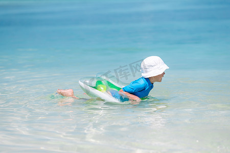 婴儿在行动摄影照片_戴着帽子的小婴儿在热带海滩游泳