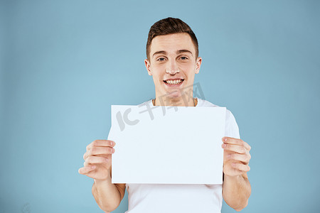 一个穿白色 T 恤的男人手里拿着一张纸，情绪是蓝色背景的裁剪视图 Copy Space