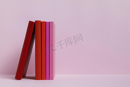 邀请函封面摄影照片_粉红色背景的彩色书籍。