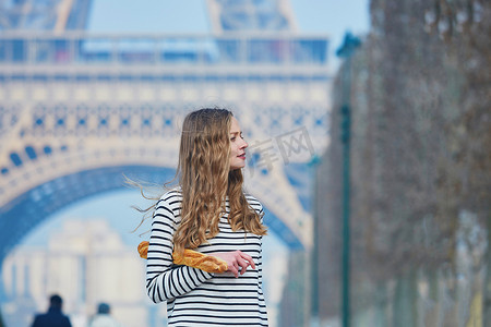 埃菲尔铁塔附近拿着传统法式长棍面包的女孩