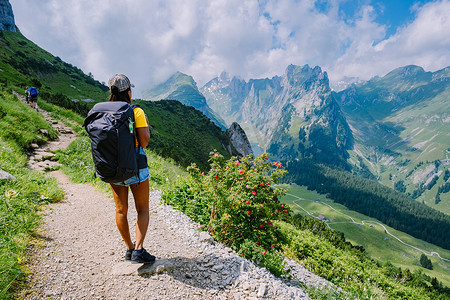 一个背着背包的女人站在山顶，这个女孩去美丽的地方旅行，到达目标，在 Saxer Luecke 的山脊，在 Alpstein Appenzell Innerrhoden 瑞士的 Kreuzberge