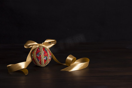 深色木质圣诞复制空间：剪纸圣诞隔离球特写为黑色背景中的金色缎带