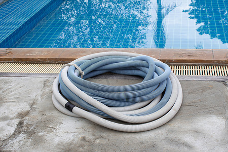 水泥地板上的游泳池真空吸尘器软管、清洁水池的手动设备。