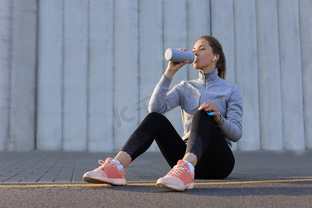 年轻的女跑步者在城市户外跑步时正在休息、喝水