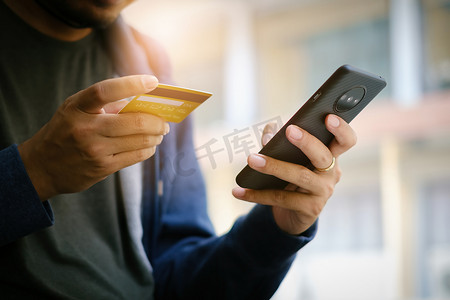 上网安全摄影照片_一个年轻人用信用卡在智能手机上上网购物。