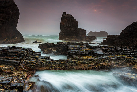 海水翻滚摄影照片_汹涌的海水覆盖着崎岖不平的海岸岩石