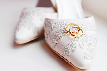 蕾丝丝织物鞋上的金色结婚戒指。