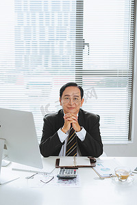 高级金融亚洲商人坐在电脑前的工作站上。
