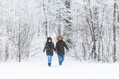 热恋中的年轻情侣在白雪皑皑的森林里散步。