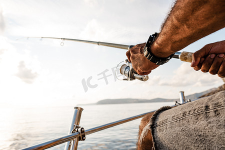在公海帆船上钓鱼时男性手持钓鱼竿的特写