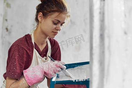 装修中摄影照片_开朗的女人在房屋装修内部粉刷一个房间