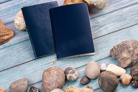 主题旅行摄影照片_蓝色木质背景上的文件、石头和贝壳。旅行主题
