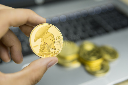 男性商人手持树泰坦比特币，背景是笔记本电脑键盘和一堆金币。