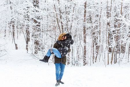 恋爱中的年轻情侣在白雪皑皑的森林里玩得开心。