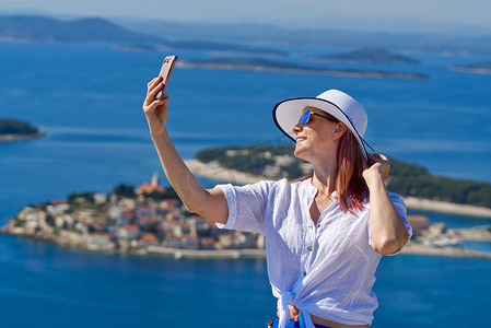 旅游博客摄影照片_美丽的蓝色亚得里亚海和舒适的岛屿背景克罗地亚，戴着白色草帽的旅游女性