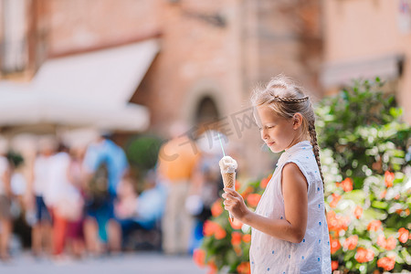 可爱的小女孩在夏天在户外吃冰淇淋。