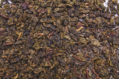 乌龙茶摄影照片_在白色背景和特写镜头的牛奶乌龙茶。作为背景的干乌龙茶叶子。