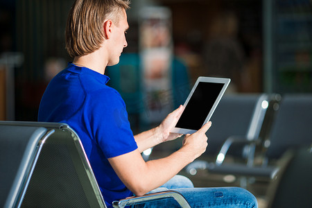 强势登入摄影照片_在机场等待登机时携带笔记本电脑的年轻人