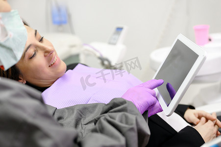 医疗保健概念-女牙医在牙科诊所办公室向女病人展示平板电脑。