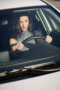 城市背景中驾驶白色汽车的黑发女性