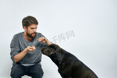 男人在室内训练狗，用手做手势来执行模型的命令