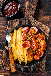 Currywurst 香肠与咖喱香料在 wursts 上供应法式炸薯条在平底锅中。