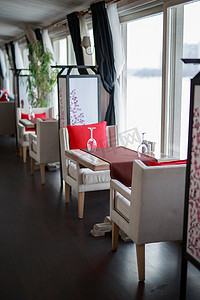 装饰质感摄影照片_桌子上放着两个玻璃杯，餐厅舒适的内部质感木制墙桌靠近大光窗的窗户，餐厅舒适的内部质感木墙