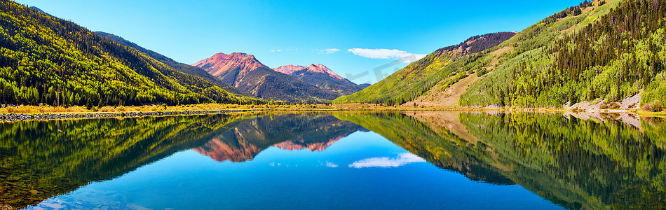 树环绕摄影照片_山中湖泊全景，四周环绕着秋树和红沙山峰