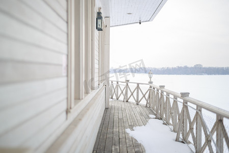 木制复古露天甲板上白雪，旧剥落油漆浅牛奶色，墙上挂着钢铜灯笼，下雪的冬天，雪躺在河上，地球的远岸是 vi