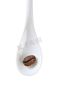 白色勺子上的单一咖啡豆，隔离在白色