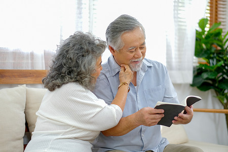 在客厅看书时，老妇人抚摸老人的脸，他们看起来很开心。