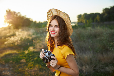 手里拿着相机的女摄影师微笑着红唇帽黄色T恤夏日大自然