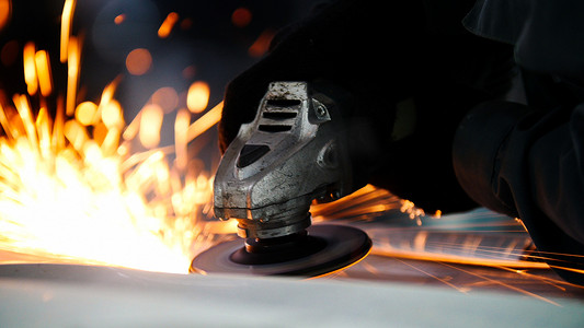 制造业服务摄影照片_汽车服务 — 工人用圆锯打磨金属结构，特写