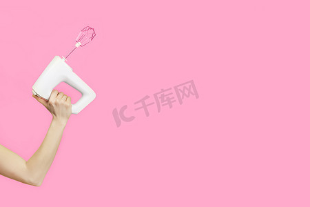 白色厨房搅拌机在女性手中隔离在粉红色背景。
