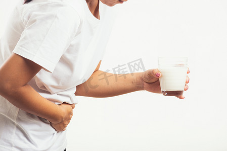 女人用手拿着玻璃牛奶，她胃疼得厉害