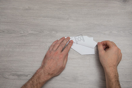 如何在带手臂的木桌上制作折纸纸飞机一步一步的照片说明。